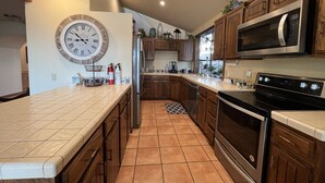 A modern kitchen with wooden cabinets, a stainless steel refrigerator, a microwave, and an oven. - Incredible Views from Smith Point (Bradley)