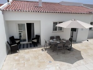 Enjoy dining al fresco under the shade of a large umbrella on this outdoor patio, complete with a round table and comfortable seating.