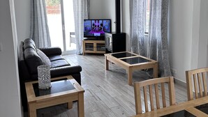 A modern living room with a black sofa, wooden coffee table, and a TV on a stand. - Cosy refurbished 3 bedroom Vila in a quiet area 2km  from town center (Lagos)