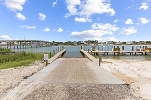 Un muelle de hormigón que conduce a un embarcadero, con vista a un puente y edificios a lo lejos.
