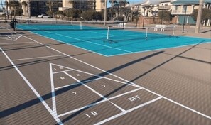 Una cancha de tenis con red, líneas delimitadoras y una zona de estar con bancos.