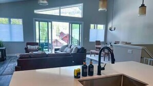 A modern kitchen with a large island, a dining area with a table and chairs, and a living room with a sofa and a view of the outdoors. - Inviting Townhouse at Purgatory (Durango)