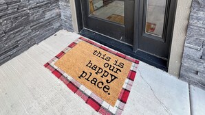 A front door with a glass panel, a doormat with a message, and a stone wall. - Inviting Townhouse at Purgatory (Durango)