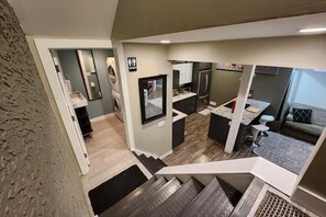 A modern interior with a kitchen, a dining area, and a staircase leading to another level.