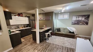A compact living space with a kitchenette, a dining area, and a seating area with a sofa and chairs.