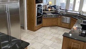 A modern kitchen with wooden cabinets, stainless steel appliances, and a large island. - Poolside Paradise on Cross Lake (Shreveport)