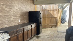 A kitchen with a stone floor, wooden cabinets, a black refrigerator, and a gas stove. - Poolside Paradise on Cross Lake (Shreveport)