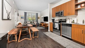 A modern kitchen with wooden cabinets, stainless steel appliances, and a dining area with a wooden table and benches. - The Found Boutique 1 bdrm haven for relaxation. (Traverse City)