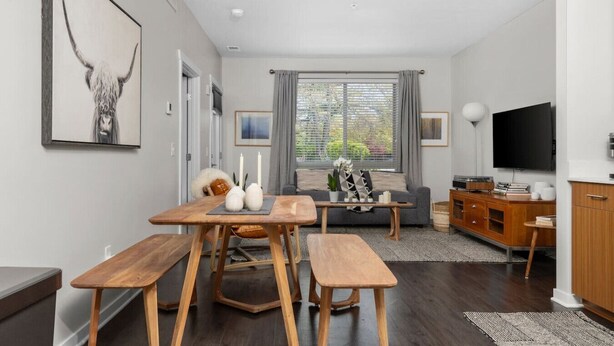 A modern living room with a wooden dining table, a sofa, and a TV. - The Found Boutique 1 bdrm haven for relaxation. (Traverse City)