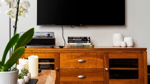 A wooden TV stand with a flat-screen TV mounted above it, a few books, and decorative items. - The Found Boutique 1 bdrm haven for relaxation. (Traverse City)