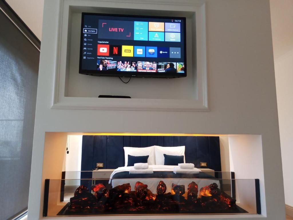 Habitació d'hotel moderna amb televisió de pantalla plana penjada sobre un llit, una taula de cafè de vidre amb objectes decoratius i un panell de capçal de llit de color fosc.