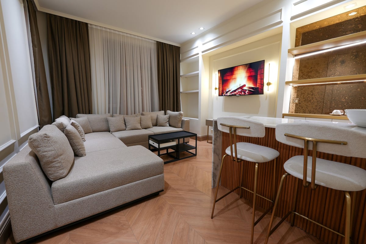 A modern living room with a sofa, coffee table, and bar stools.