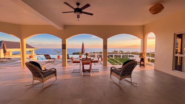 A covered outdoor area with a pool, chairs, and a view of the ocean. - Coral Bay Chateau - Luxury Villa in Treasure Beach (Treasure Beach)