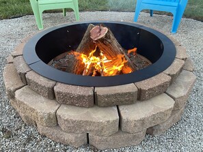 A circular stone fire pit with a black rim, surrounded by a gravel area. - Sunset Getaway (Lebanon)