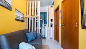 A modern living room with a sofa, a wooden partition, and a kitchen in the background. - Casa Pé N'Areia (Ferrel)
