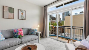 A modern living room with a grey sofa, colorful pillows, a white coffee table, and a balcony with a city view. - Belltown Perch explore like a local (Seattle)
