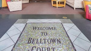 A lobby with a reception desk, sofas, a fireplace, and a "Welcome to Belltown Court" sign. - Belltown Perch explore like a local (Seattle)