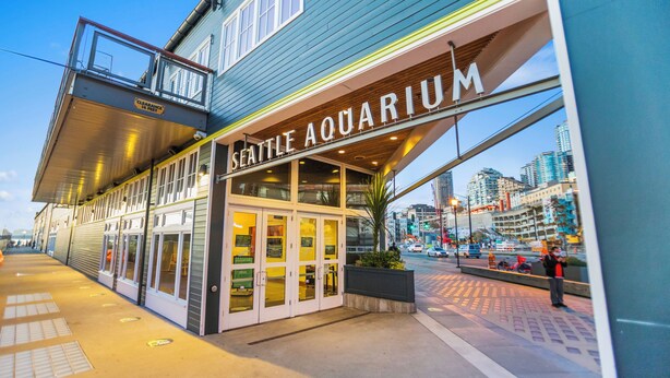 The Seattle Aquarium building with a glass entrance and a view of the cityscape in the background. - Belltown Perch explore like a local (Seattle)