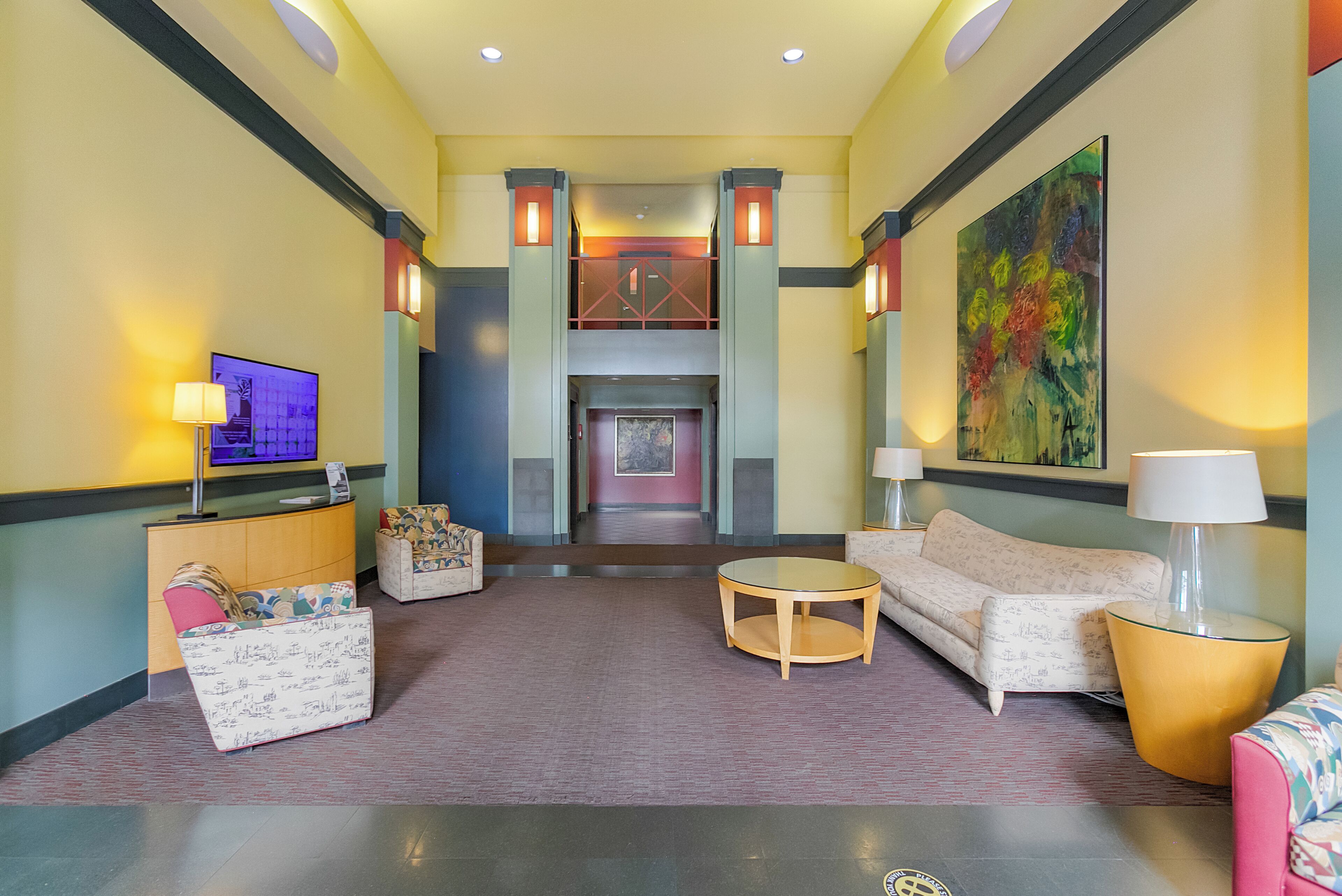 A lobby with a reception desk, seating area, and a staircase leading to an upper level.