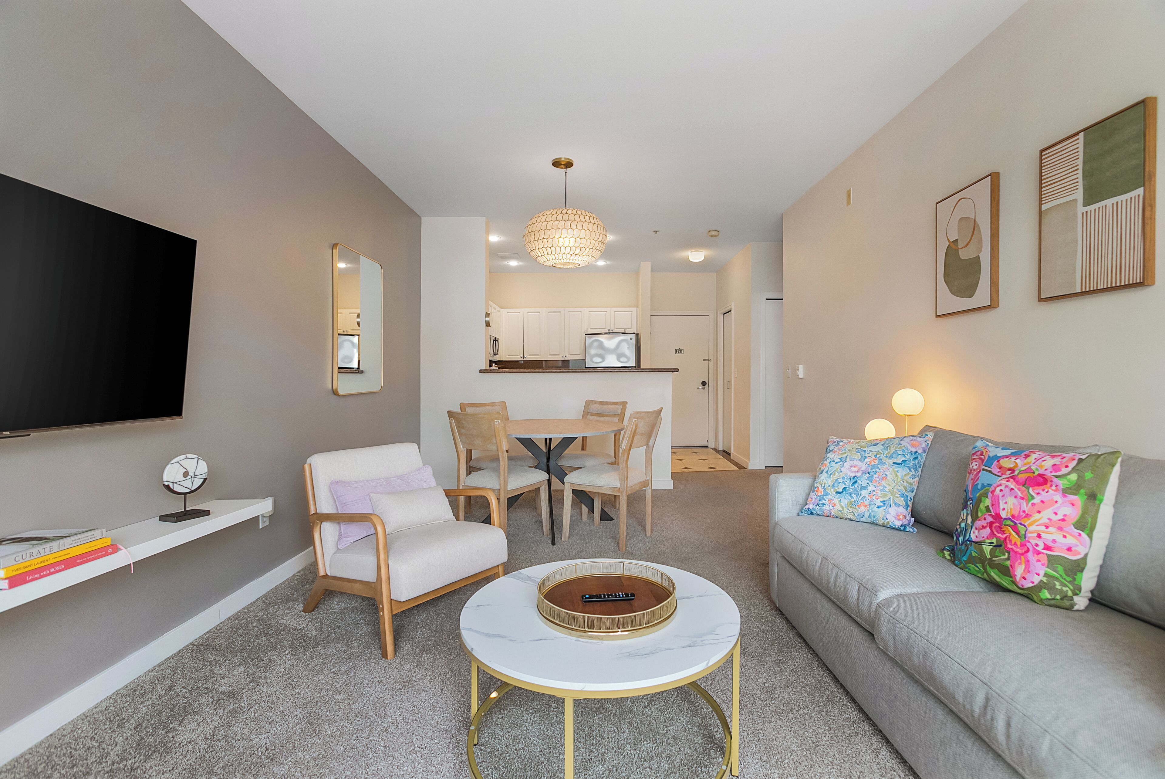 A modern living room with a sofa, coffee table, and a dining area with chairs and a table.