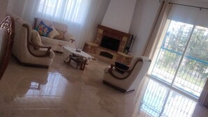 Ein geräumiges Wohnzimmer mit Kamin, einer Couch, einem Couchtisch und einem Sessel.