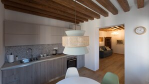 A modern kitchen with wooden beams, a hanging light fixture, and a dining area with a table and chairs. - Aponalview apartment  027042-LOC-12481 (Venezia)