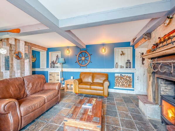 Una sala de estar acogedora con chimenea, pared azul y techo de madera.