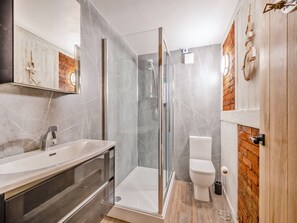 Un baño moderno con ducha de vidrio, lavamanos blanco y retrete.