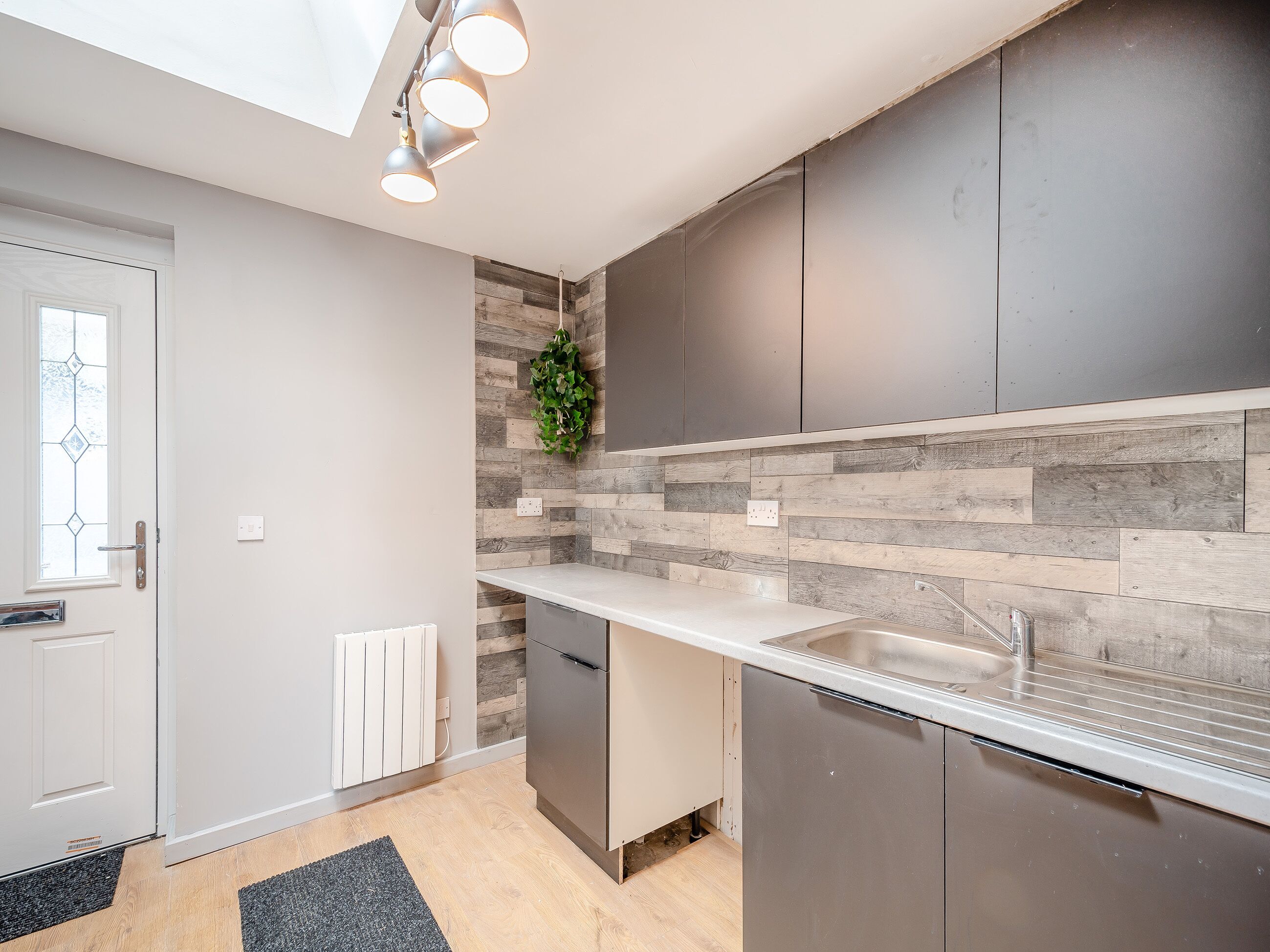 Eine moderne Küche mit eingebautem Geschirrspüler, einer Edelstahlspüle und einer Holzrückwand.