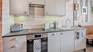 Una cocina moderna con armarios grises, un horno de acero inoxidable, un hervidor y un fregadero.