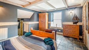 Un dormitorio con cama, cabecero de madera, cómoda y ventana con vistas.