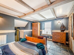 Un dormitorio con cama, cabecero de madera, cómoda y ventana con vistas.