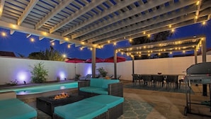 Une terrasse extérieure avec une piscine, un espace salon et un coin barbecue.