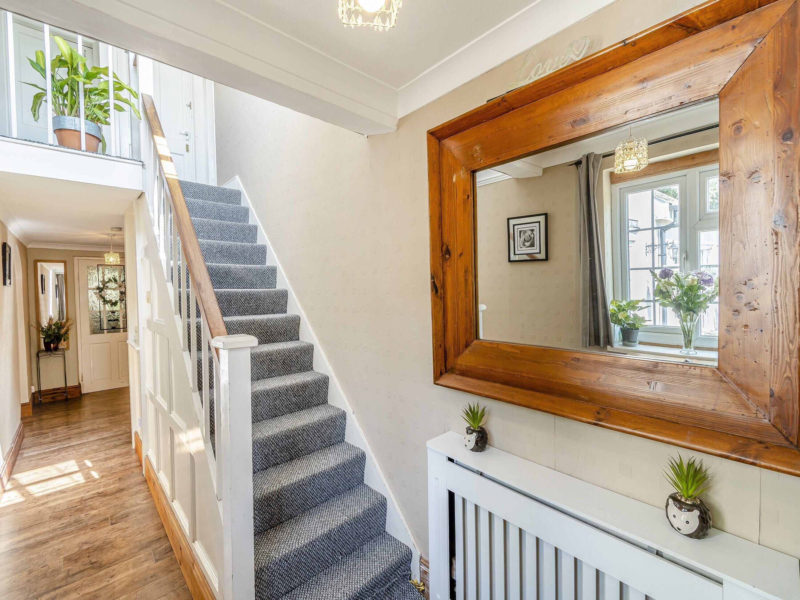A staircase with a wooden railing, a white radiator, and a mirror on the wall.