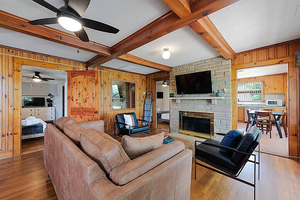 A spacious living room with a fireplace, wooden walls, and a television mounted above it.