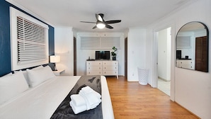 A modern hotel room with a bed, a ceiling fan, a TV, a dresser, and a mirror. - Lake Hickory Trio w/Boat Slip (Catawba County)