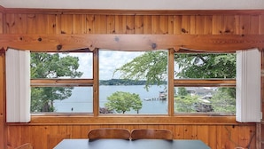 A room with a large window overlooking a lake, wooden walls, and a table with chairs. - Lake Hickory Trio w/Boat Slip (Catawba County)
