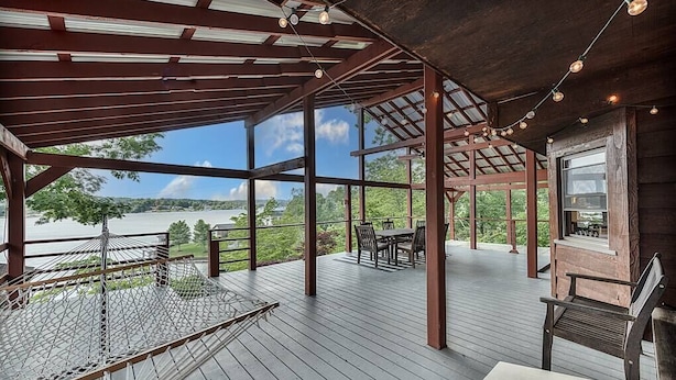 A covered deck with a hammock, outdoor seating, and a grill area overlooking a body of water. - Lake Hickory Trio w/Boat Slip (Catawba County)
