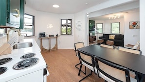 A modern kitchen with a white stove, wooden flooring, and a dining area with a black table and chairs. - Lake Hickory Trio w/Boat Slip (Catawba County)