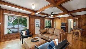 A spacious living room with wooden walls and ceiling, large windows, a leather sofa, a coffee table, and a foosball table. - Lake Hickory Trio w/Boat Slip (Catawba County)