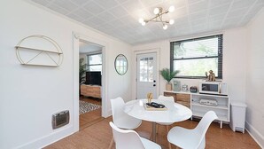 A modern dining area with a round white table, white chairs, and a ceiling light fixture. - Lake Hickory Trio 1 BR Pink Unit (Catawba County)