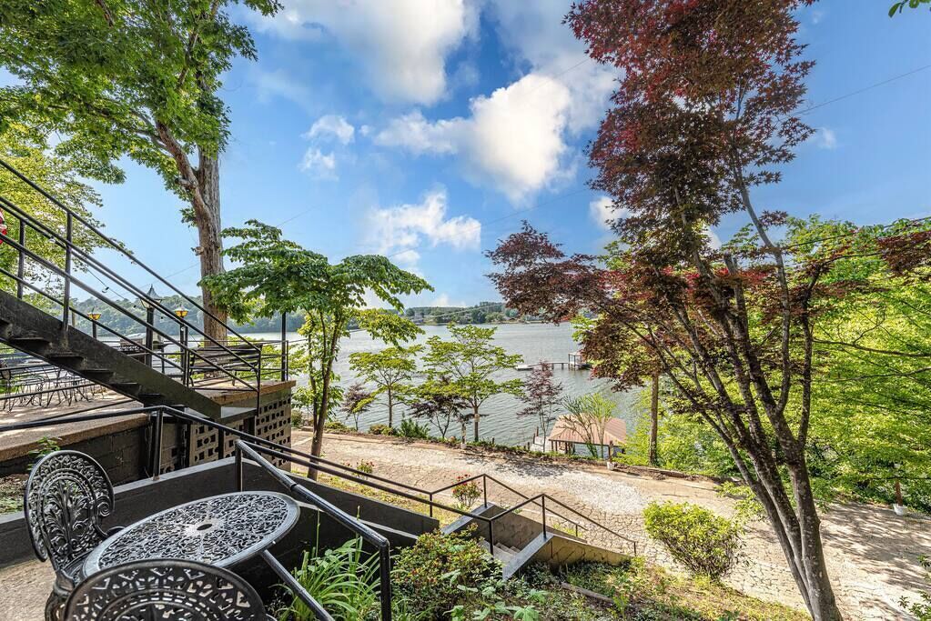 A staircase leading to a terrace overlooking a lake, with outdoor seating and trees.
