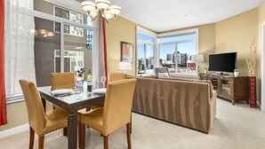 A well-lit living room with a dining area, a sofa, and a television. - Corner Unit in the Middle of It All (Seattle)