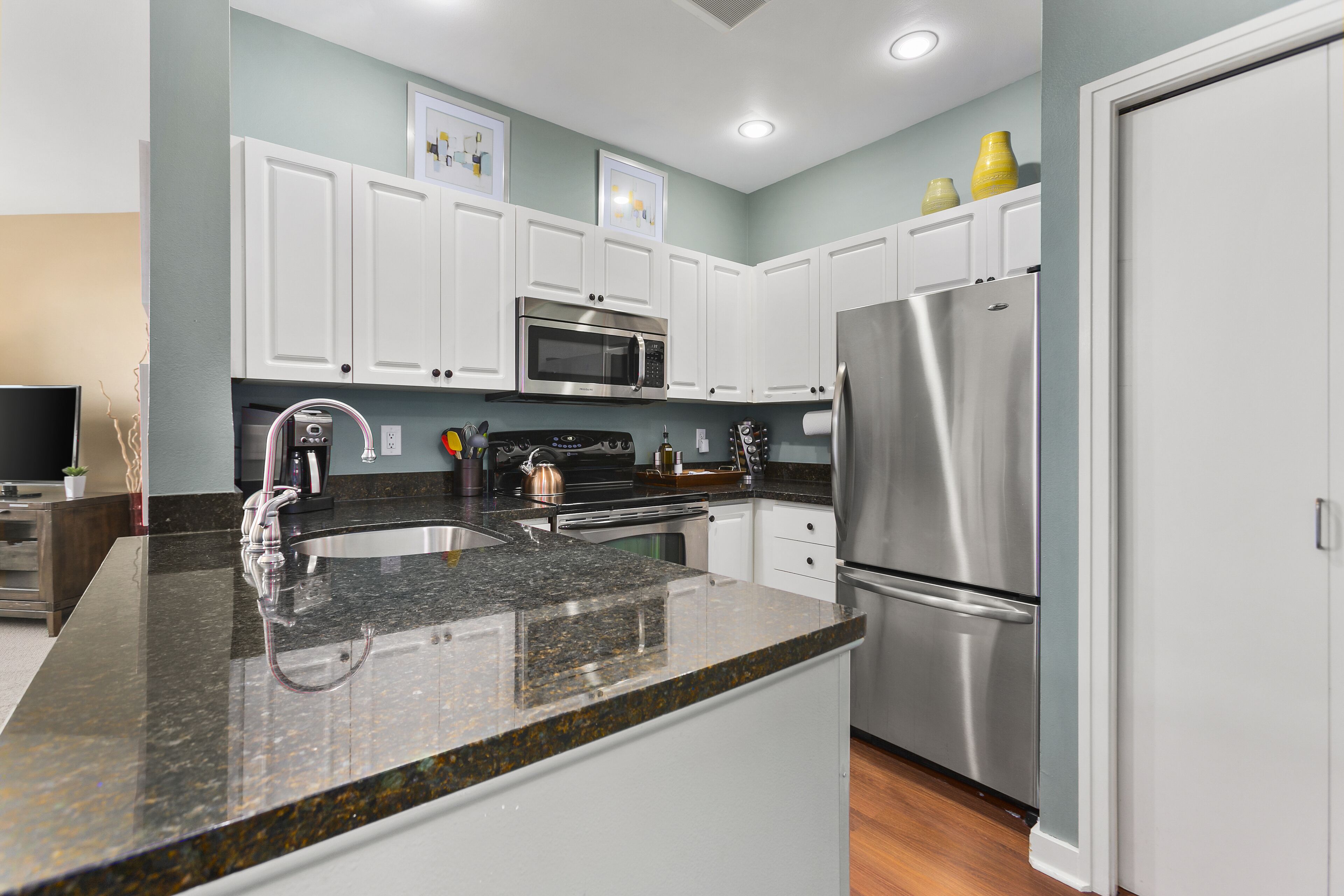 A modern kitchen with white cabinets, stainless steel appliances, and granite countertops.