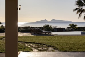Un espace aménagé au bord de la piscine, avec des chaises longues et une vue sur la mer et les montagnes.