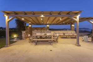Une terrasse extérieure agrémentée d’une pergola, de murs en pierre et offrant une vue sur le paysage.