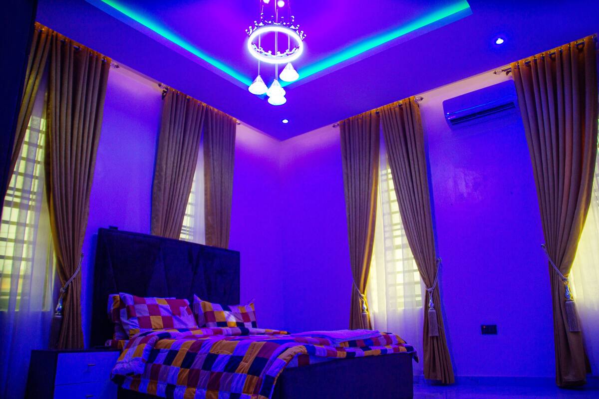 A bedroom with a bed, curtains, and a chandelier.