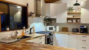Una cocina moderna con encimeras de madera, armarios blancos, horno empotrado, microondas y un lavamanos.