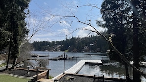 Un parque junto al lago con un muelle de madera, un camino de piedra y una zona cubierta de césped.