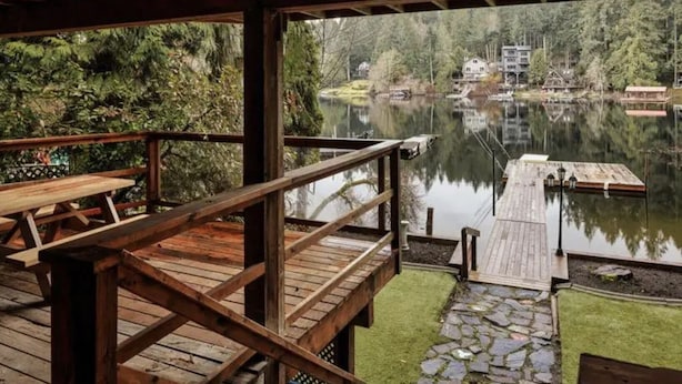 Una terraza de madera con vistas a un lago tranquilo y bosque circundante.